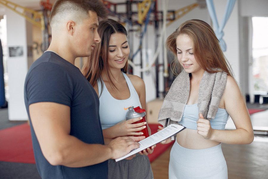 Personal trainer onboarding new clients at the gym with a consultation checklist"