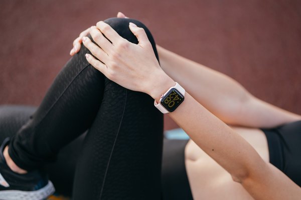 Close-up of a woman wearing a smartwatch while stretching during a workout, focusing on fitness tracking.
