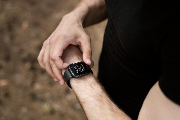 Everfit Coach Review: Male athlete checking workout metrics on a smartwatch during an outdoor fitness session.