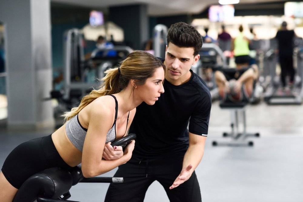 My PT Hub App Review 2025 Personal trainer guiding woman during back extension at gym