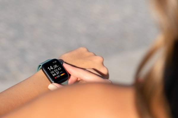 Close-up of a person checking workout session data on a smartwatch, displaying time, duration, heart rate, and calories burned.