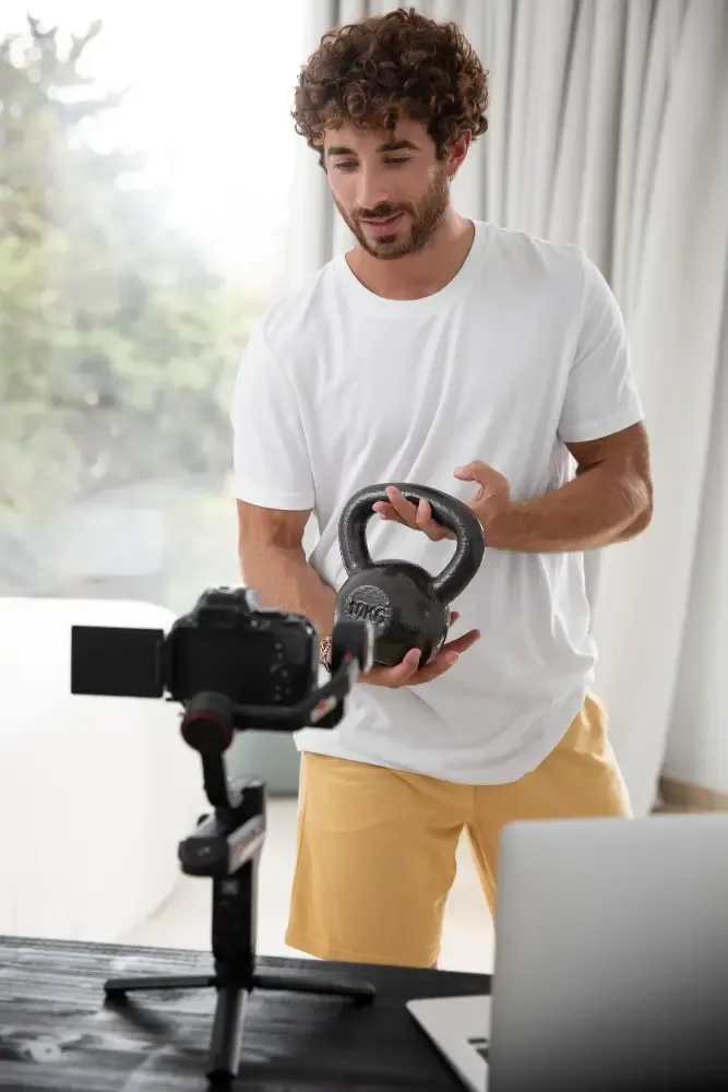Fitness coach recording a kettlebell workout tutorial at home for online clients