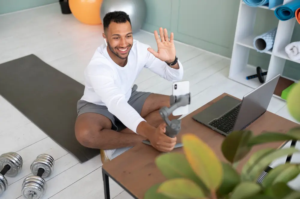Personal trainer waving to online clients during live coaching session in home workout studio
