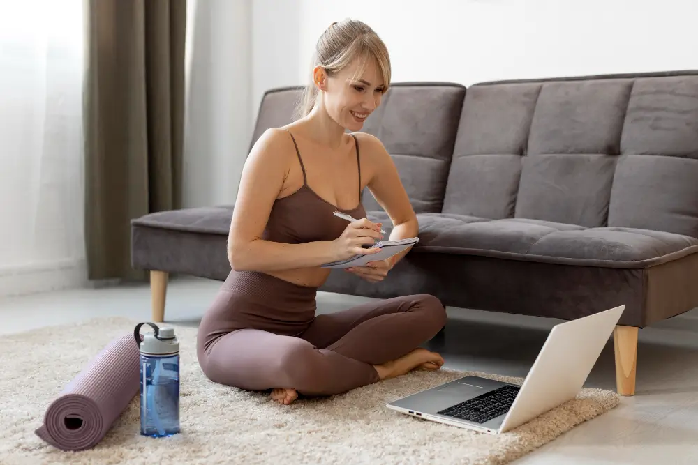 Coaching Tools For Online Personal Trainers In 2025 Fitness coach taking notes while training clients via online platform