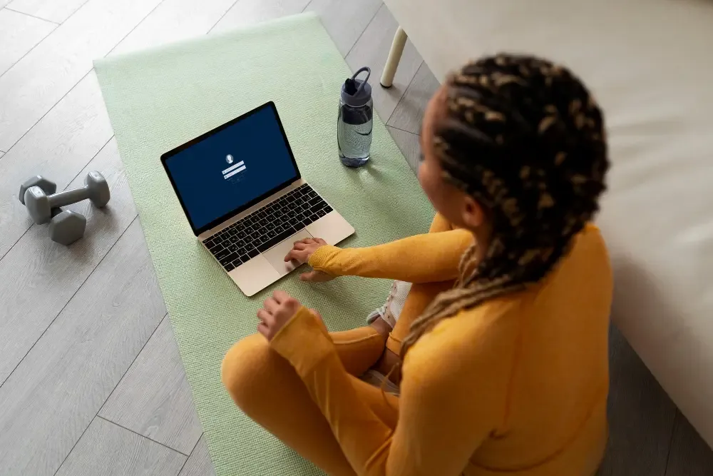 Online fitness training at home with laptop and exercise equipment