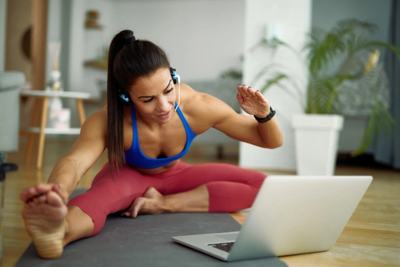 Female fitness coach stretching during a live Zenfit app workout session from home.