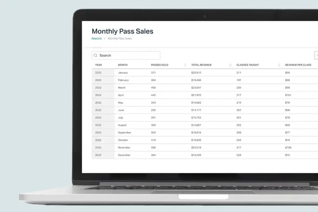 Punchpass monthly pass sales report on laptop showing revenue and class statistics.